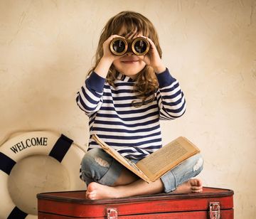 Kind mit Buch und Fernglas